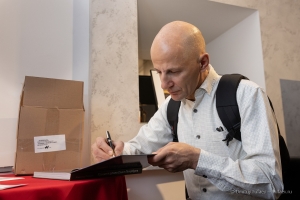 Александр Петросян подписывает книгу на открытии фотовыставки Петербург Александра Петросяна в Фотолетописи Санкт-Петербурга на Невском проспекте 88. Декабрь 2021года.