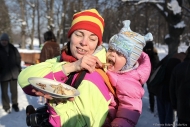 Мама кормит ребенка блином на масленице. Фотограф Дмитрий Фуфаев.