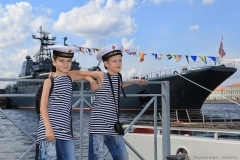 Мальчики в матросской форме на причале в день Военно-Морского флота на фоне военного корабля. Военный корабль с праздничными флагами на Неве в Санкт-Петербурге. Детский фотограф Дмитрий Фуфаев.